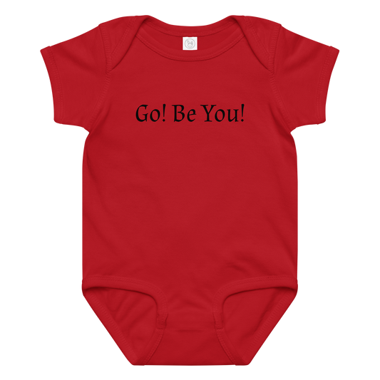 "Go! Be You!" printed on a red baby jersey bodysuit laying on a flat surface amongst other clothes