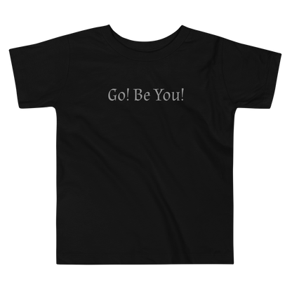 "Go! Be You!" printed on a black toddler short sleeve tee laying on a flat surface