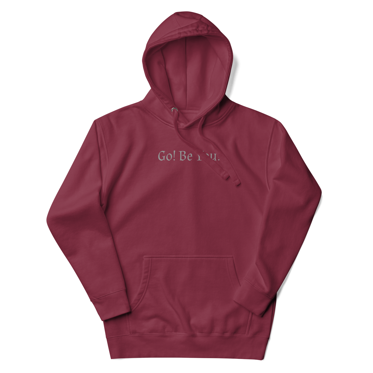 "Go! Be You!" printed on a maroon unisex hoodie laying on a flat surface with the hood up