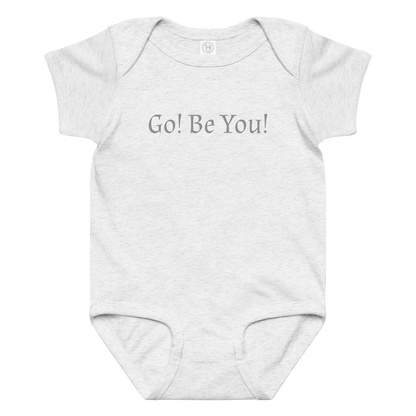 "Go! Be You!" printed on a ash baby jersey bodysuit laying on a flat surface amongst other clothes