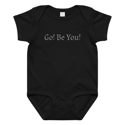 "Go! Be You!" printed on a black baby jersey bodysuit laying on a flat surface amongst other clothes
