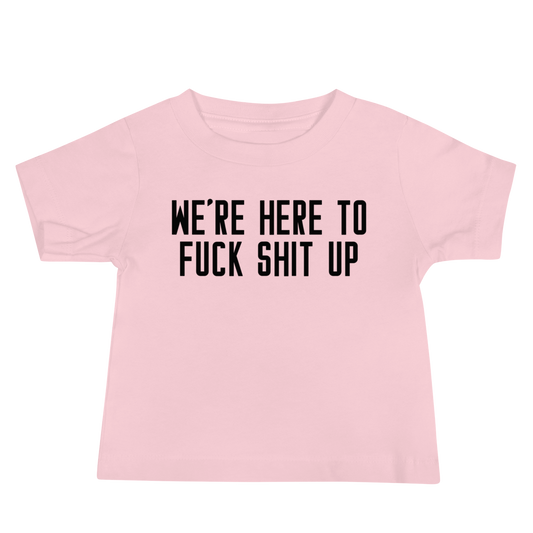 "We're Here To Fuck Shit Up" printed on a pink baby jersey short sleeve tee laying on a flat surface