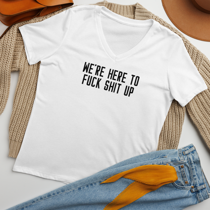 "We're Here To Fuck Shit Up" printed on a solid white blend women's relaxed v-neck t-shirt laying on a flat surface amongst other clothes