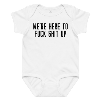 "We're Here To Fuck Shit Up" printed on a white baby jersey bodysuit laying on a flat surface amongst other clothes