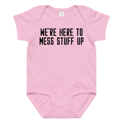 "We're Here To Mess Stuff Up" printed on a pink baby jersey bodysuit laying on a flat surface amongst other clothes