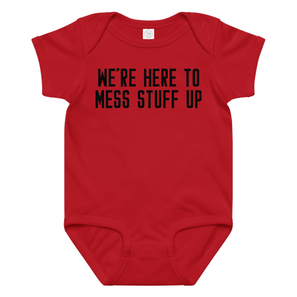 "We're Here To Mess Stuff Up" printed on a red baby jersey bodysuit laying on a flat surface amongst other clothes