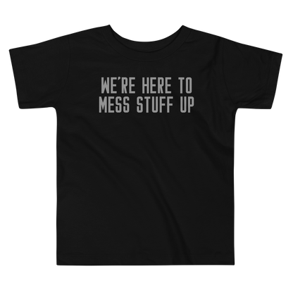"We're Here To Mess Stuff Up" printed on a black toddler short sleeve tee laying on a flat surface