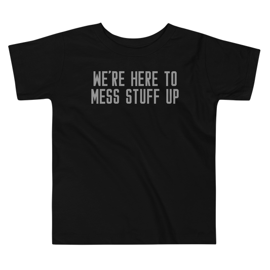 "We're Here To Mess Stuff Up" printed on a black toddler short sleeve tee laying on a flat surface