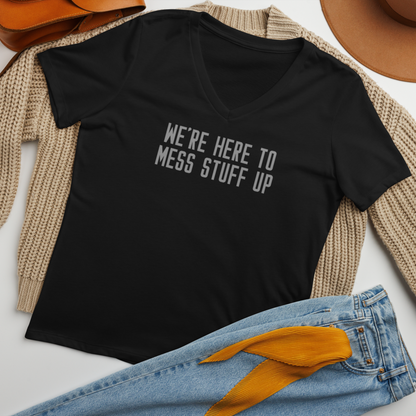 "We're Here To Mess Stuff Up" printed on a solid black blend women's relaxed v-neck t-shirt laying on a flat surface amongst other clothes