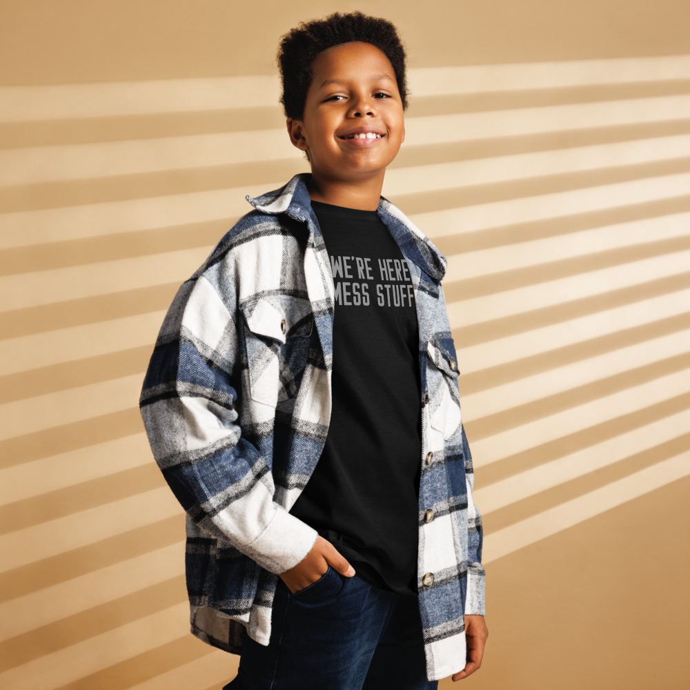 "We're Here To Mess Stuff Up" printed on a black youth classic tee worn by a male also wearing a jacket