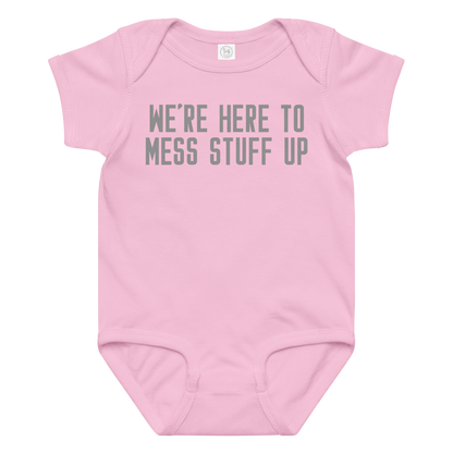 "We're Here To Mess Stuff Up" printed on a pink baby jersey bodysuit laying on a flat surface amongst other clothes