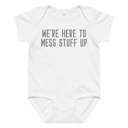 "We're Here To Mess Stuff Up" printed on a white baby jersey bodysuit laying on a flat surface amongst other clothes