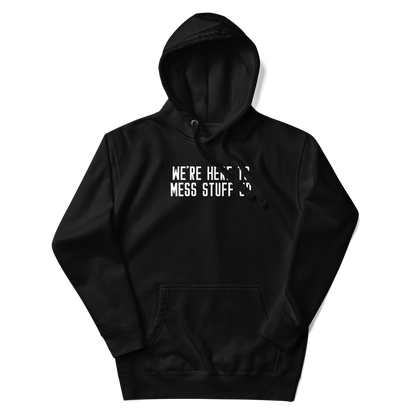 "We're Here To Mess Stuff Up" printed on a black unisex hoodie laying on a flat surface with the hood up
