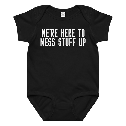 "We're Here To Mess Stuff Up" printed on a black baby jersey bodysuit laying on a flat surface amongst other clothes