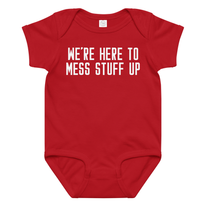 "We're Here To Mess Stuff Up" printed on a red baby jersey bodysuit laying on a flat surface amongst other clothes