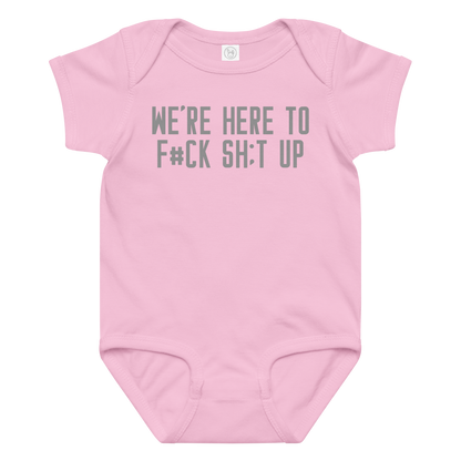 "We're Here To F#Ck Sh:t Up" printed on a pink baby jersey bodysuit laying on a flat surface amongst other clothes
