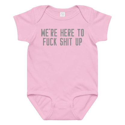 "We're Here To Fuck Shit Up" printed on a pink baby jersey bodysuit laying on a flat surface amongst other clothes