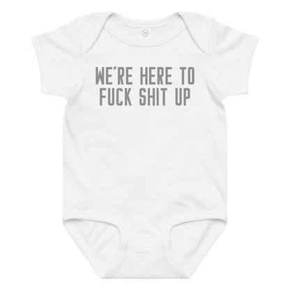 "We're Here To Fuck Shit Up" printed on a white baby jersey bodysuit laying on a flat surface amongst other clothes