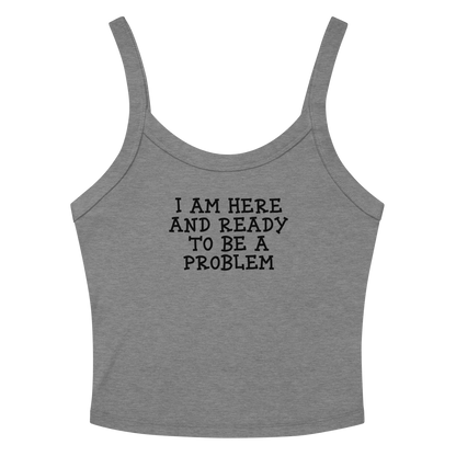 "I am here and ready to be a problem" printed on a athletic heather women's micro-rib tanktop laying on a flat surface amongst sunglasses and shorts