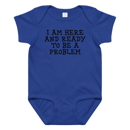 "I am here and ready to be a problem" printed on a royal baby jersey bodysuit laying on a flat surface amongst other clothes