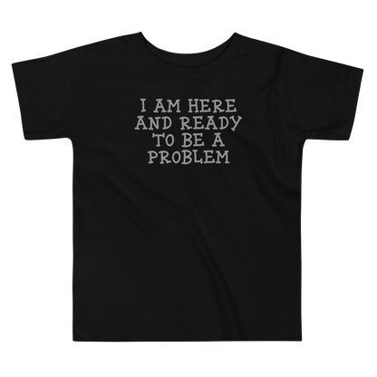 "I am here and ready to be a problem" printed on a black toddler short sleeve tee laying on a flat surface