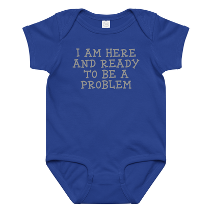 "I am here and ready to be a problem" printed on a royal baby jersey bodysuit laying on a flat surface amongst other clothes