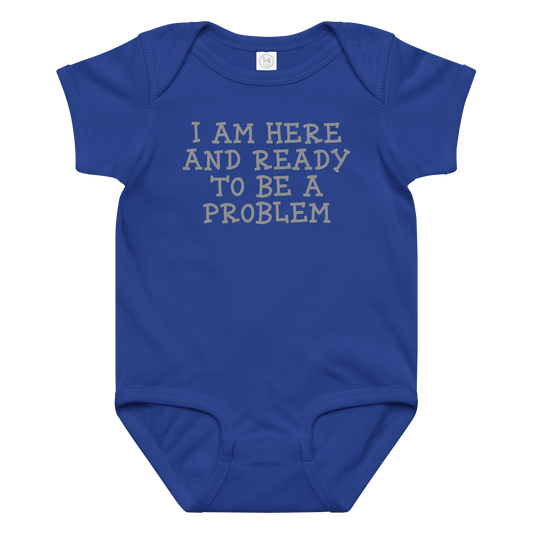 "I am here and ready to be a problem" printed on a royal baby jersey bodysuit laying on a flat surface amongst other clothes