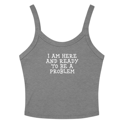 "I am here and ready to be a problem" printed on a athletic heather women's micro-rib tanktop laying on a flat surface amongst sunglasses and shorts