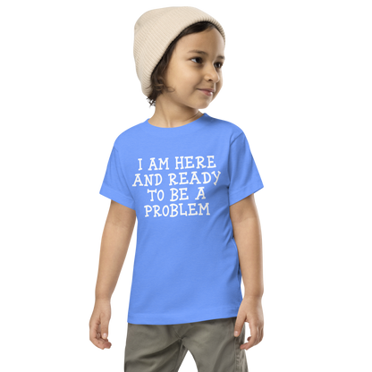 "I am here and ready to be a problem" printed on a heather columbia blue toddler short sleeve tee worn by a male wearing a cap