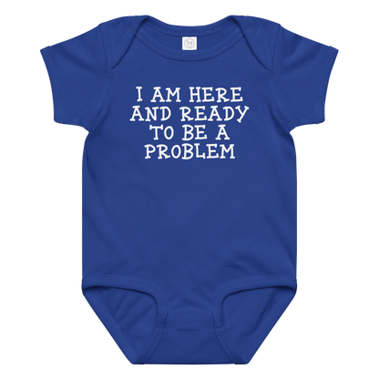 "I am here and ready to be a problem" printed on a royal baby jersey bodysuit laying on a flat surface amongst other clothes