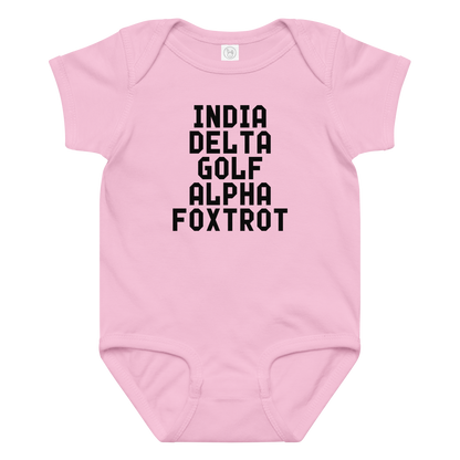"India Delta Golf Alpha Foxtrot" printed on a pink baby jersey bodysuit laying on a flat surface amongst other clothes