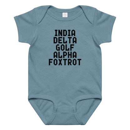"India Delta Golf Alpha Foxtrot" printed on a vintage indigo baby jersey bodysuit laying on a flat surface amongst other clothes
