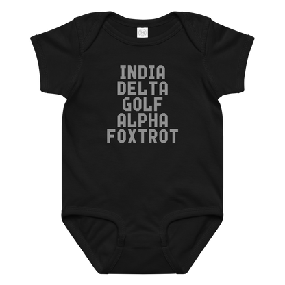 "India Delta Golf Alpha Foxtrot" printed on a black baby jersey bodysuit laying on a flat surface amongst other clothes