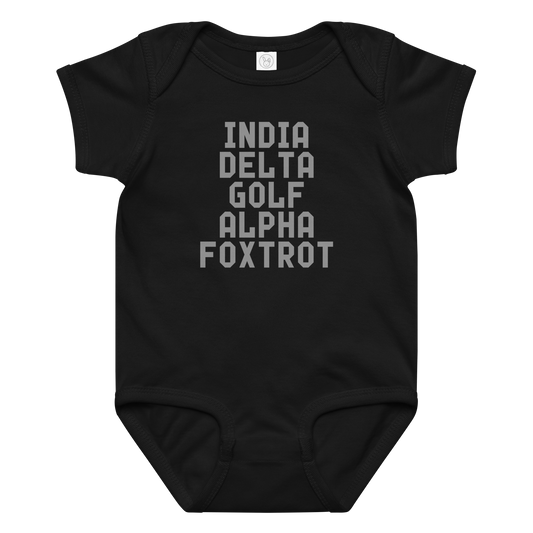 "India Delta Golf Alpha Foxtrot" printed on a black baby jersey bodysuit laying on a flat surface amongst other clothes