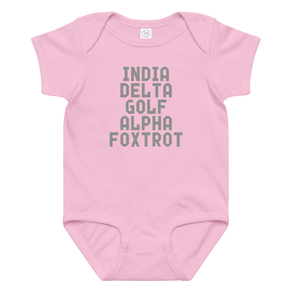 "India Delta Golf Alpha Foxtrot" printed on a pink baby jersey bodysuit laying on a flat surface amongst other clothes