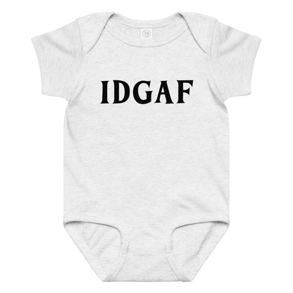 "IDGAF" printed on a ash baby jersey bodysuit laying on a flat surface amongst other clothes