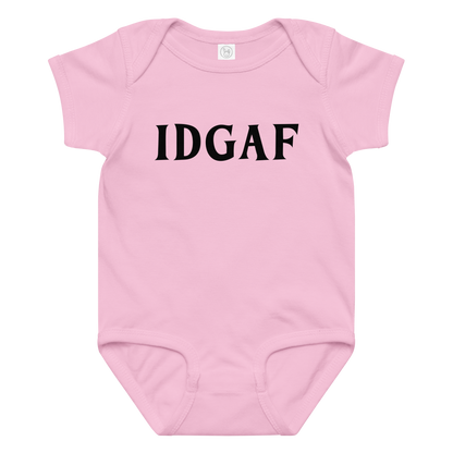"IDGAF" printed on a pink baby jersey bodysuit laying on a flat surface amongst other clothes