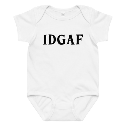 "IDGAF" printed on a white baby jersey bodysuit laying on a flat surface amongst other clothes