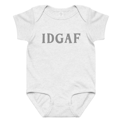 "IDGAF" printed on a ash baby jersey bodysuit laying on a flat surface amongst other clothes