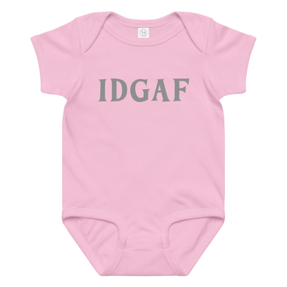 "IDGAF" printed on a pink baby jersey bodysuit laying on a flat surface amongst other clothes