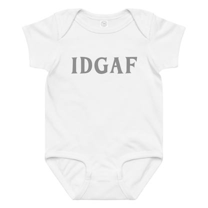 "IDGAF" printed on a white baby jersey bodysuit laying on a flat surface amongst other clothes