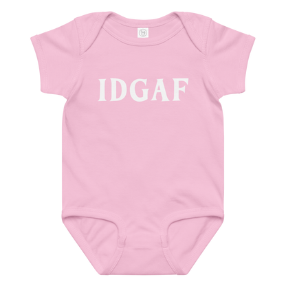 "IDGAF" printed on a pink baby jersey bodysuit laying on a flat surface amongst other clothes