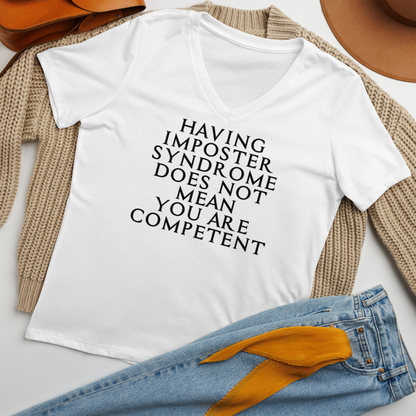 "Having Imposter Syndrome does not mean you are competent" printed on a solid white blend women's relaxed v-neck t-shirt laying on a flat surface amongst other clothes