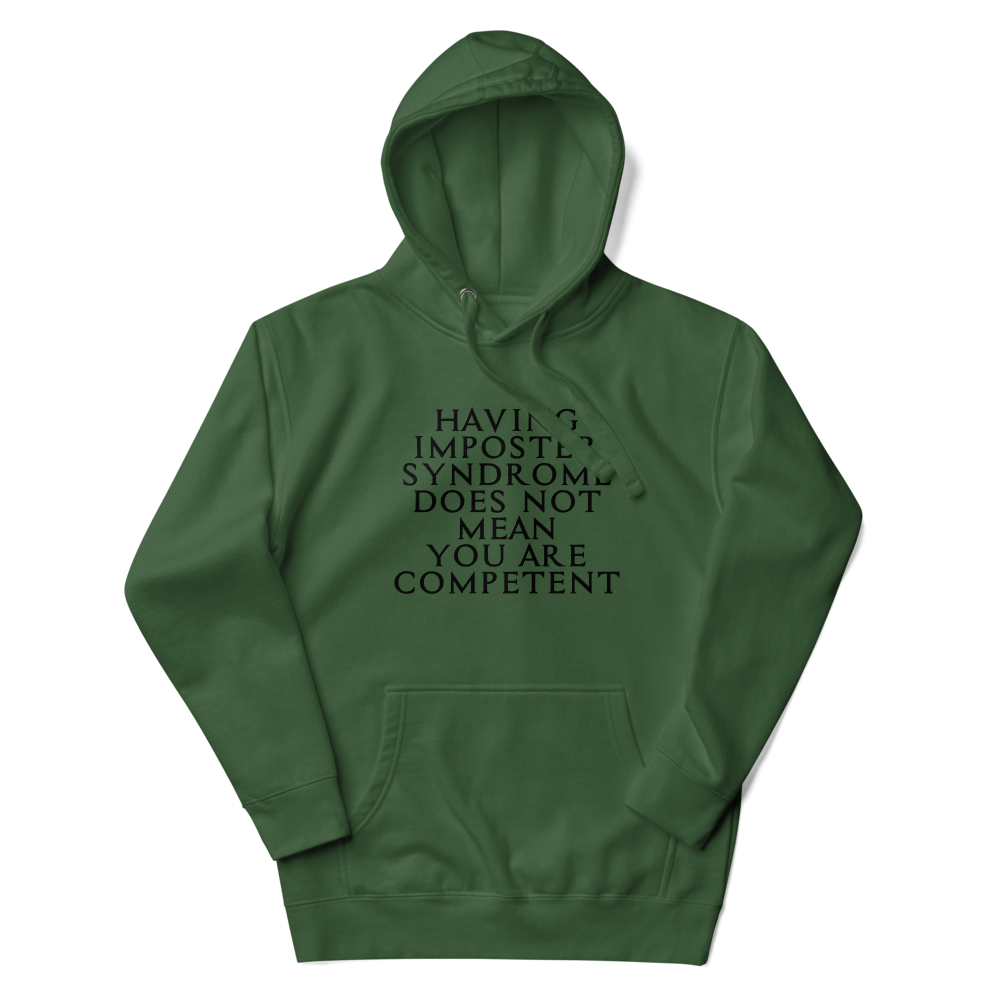 "Having Imposter Syndrome does not mean you are competent" printed on a forest green unisex hoodie laying on a flat surface with the hood up