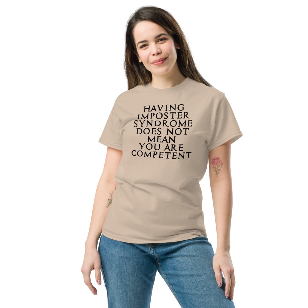 "Having Imposter Syndrome does not mean you are competent" printed on a sand unisex classic tee worn by a female