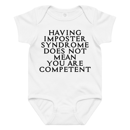"Having Imposter Syndrome does not mean you are competent" printed on a white baby jersey bodysuit laying on a flat surface amongst other clothes