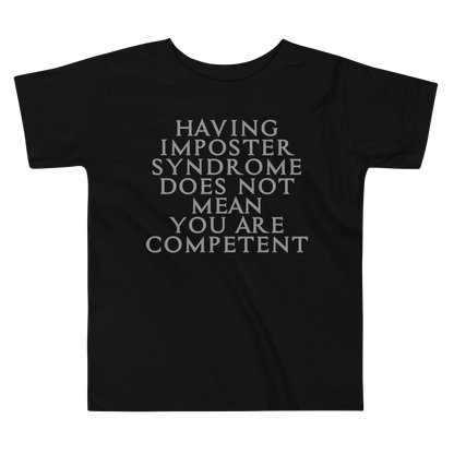 "Having Imposter Syndrome does not mean you are competent" printed on a black toddler short sleeve tee laying on a flat surface