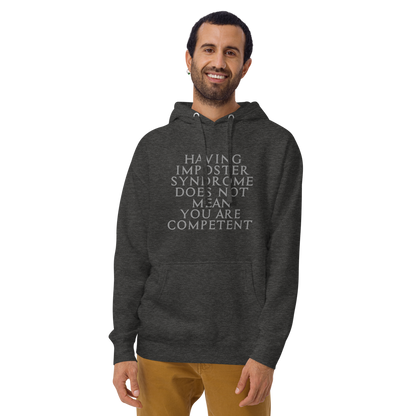"Having Imposter Syndrome does not mean you are competent" printed on a charcoal heather warn by a male