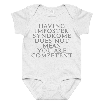 "Having Imposter Syndrome does not mean you are competent" printed on a ash baby jersey bodysuit laying on a flat surface amongst other clothes