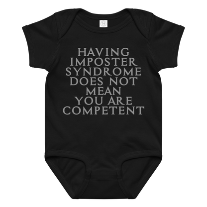 "Having Imposter Syndrome does not mean you are competent" printed on a black baby jersey bodysuit laying on a flat surface amongst other clothes